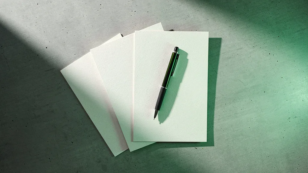 Porto Seguro Consórcios: mesa de escritório minimalista com folhas de papel sobrepostas e caneta sobre superfície de concreto claro