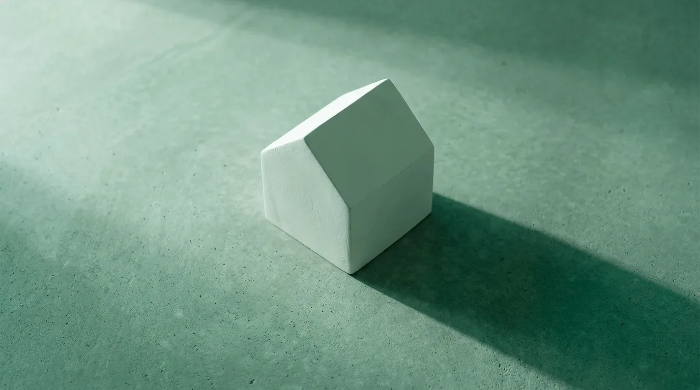 maquete branca de casa sobre superfície de concreto com luz lateral e sombra longa (consórcio de casa Santander)